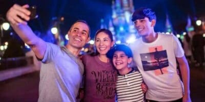 a family takes a selfie in front of cinderella castle in magic kingdom at night
