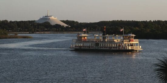 A boat sails across Seven Seas Lagoon with Space Mountain in the background
