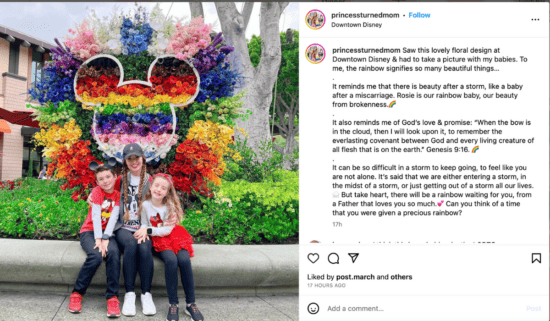 An Instagram post in which a Disney influencer and her two children pose in front of a rainbow mickey mouse head floral display. 