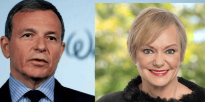 A Disney executive in a sharp suit and a woman with short blonde hair pose for a cheerful photo, radiating the friendly energy fans expect from Disney leaders—even as rumors swirl about leadership changes during a challenging time for the company.