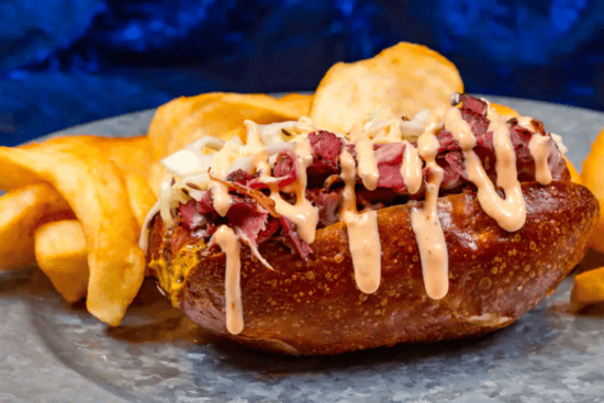 A pastrami pretzel dog served with kettle chips for Rogers: The Musical. 