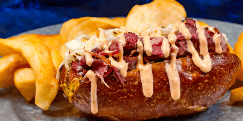 A pastrami pretzel dog served with kettle chips for Rogers: The Musical.
