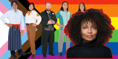 Latondra Newton posed in front of a group of Disney Cast Members representing the disney diversity and inclusion department stand in front of a pride flag.