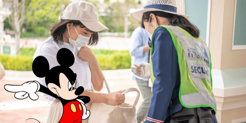 mickey Mouse with a Disney Parks security Cast Member inspecting a Guest's bag
