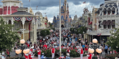 A crowd of people on Main Street, U.S.A., watching the flag ceremony in front of Cinderella Castle at Walt Disney World.