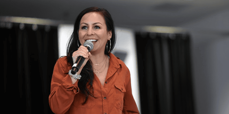 Anjelah Johnson speaking into a microphone.