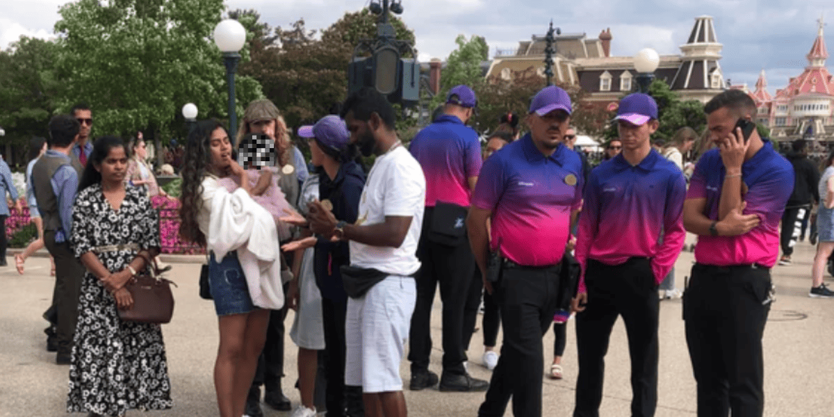 A group of Disney Cast Members surrounds a family at Disneyland Paris.