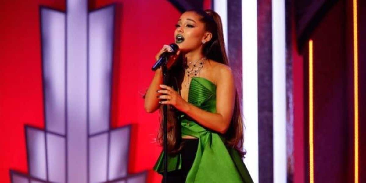 Ariana Grande in a green dress, singing.