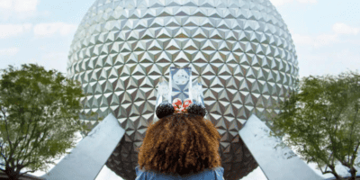 A girl wearing Mickey ears in front of Spaceship Earth at EPCOT's International Food and Wine Festival