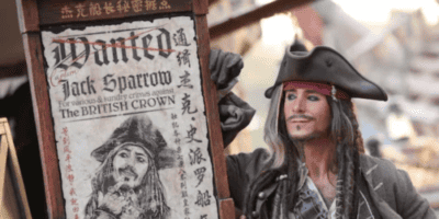 A Disney Character performer as Captain Jack Sparrow posing next to a wanted sign.