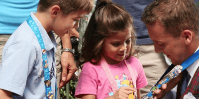 Cast Member displaying lanyard of pins for children who also of lanyards with pins on them