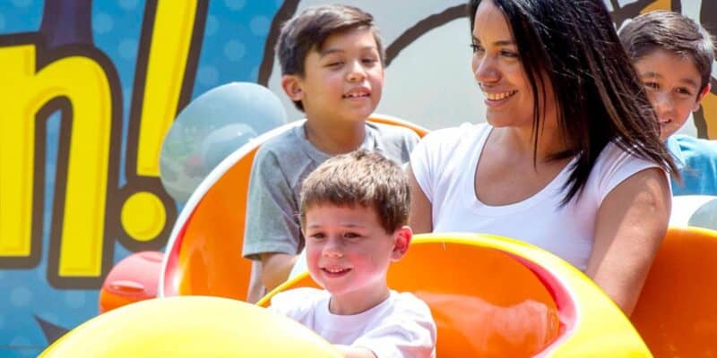 Two young Guests and an adult woman ride Snoopy's Space Buggies at Kings Dominion