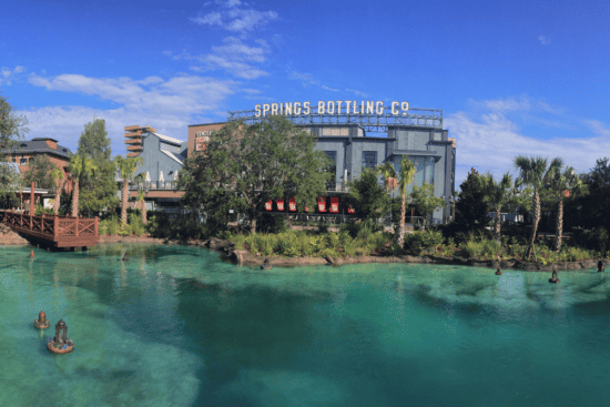 A wide-view shot of Disney Springs showing the open water and the Springs Bottling Company in the background