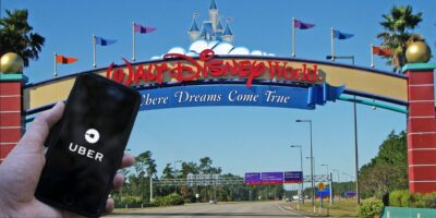 Uber on cellphone app being held at the entrance of Walt Disney World