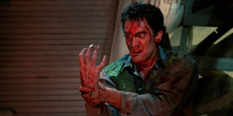 Ash Williams covered in blood and holding his hand so it won't attack him from Evil Dead