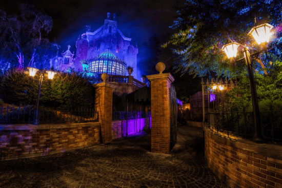 Disney World's Haunted Mansion photographed just before the gates at night while basking in a spooky glow