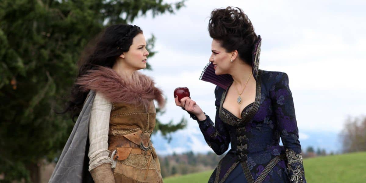 The Evil Queen holds an apple out to Snow White