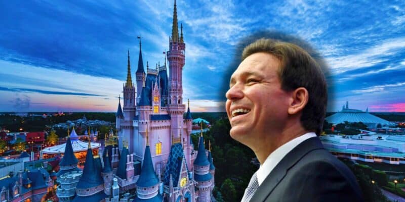 Florida Governor Ron DeSantis smiles on as the Magic Kingom castle sits in the background with clouds rolling through and Space Mountain in the background