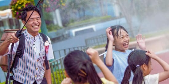 A Tokyo Disney Resort Cast Member helps keep a group of children cool with a water-filled spray gun during the intense summer months in Japan