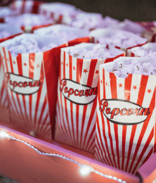 Multiple popcorn bags in tray with a string light wrapped around the tray
