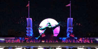 Disney California Adventure entrance at night during Halloween time at Disneyland Resort with Oogie Boogie decorations announcing the Oogie Boogie Bash
