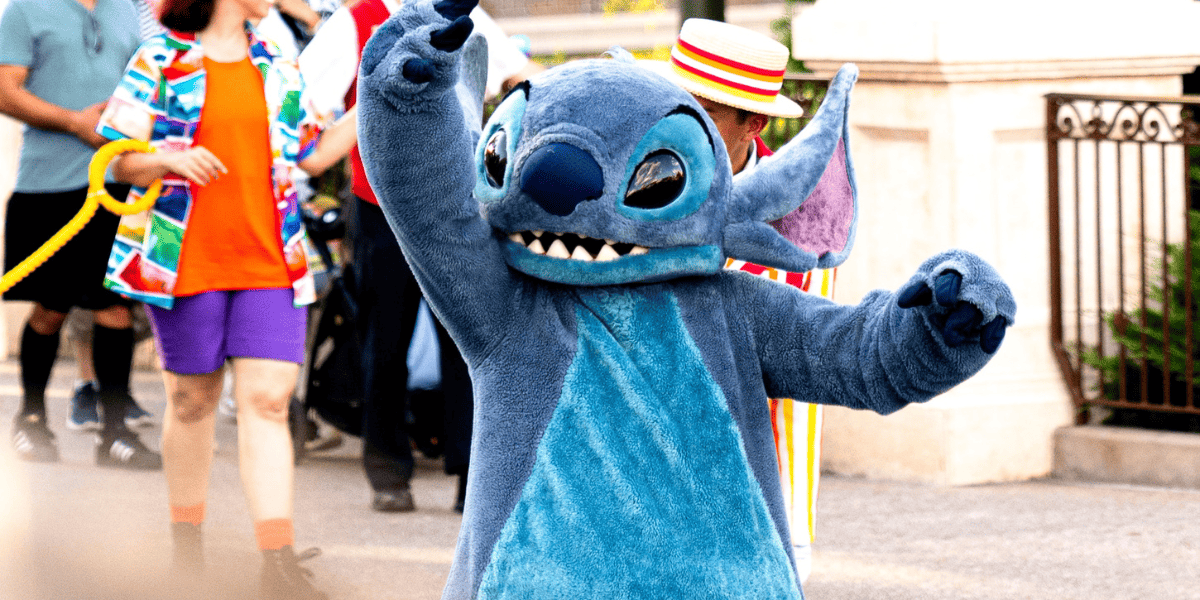 Blue Stitch character waving to the crowd at Disney World