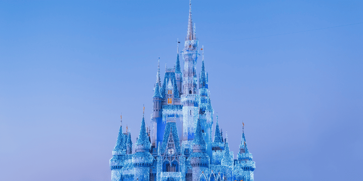 Disney's Castle pictured against a dreamy blue sky and covered in icy-blue decorations for winter