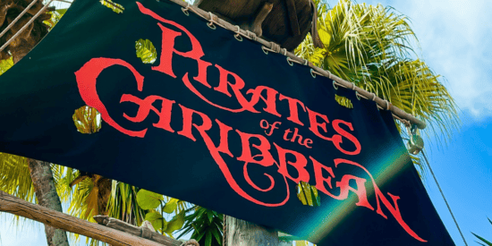 Pirates of the Caribbean flag pictured with a palm tree and clear blue sky in the background