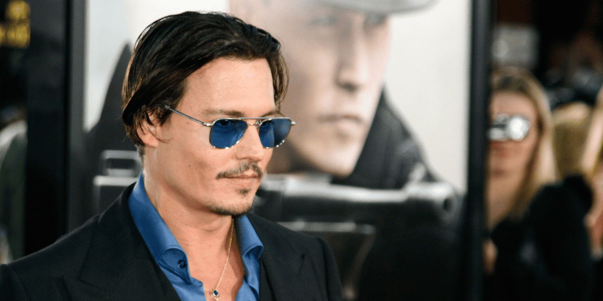 Johnny Depp posed with dark sunglasses, a blue shirt, and dark hair
