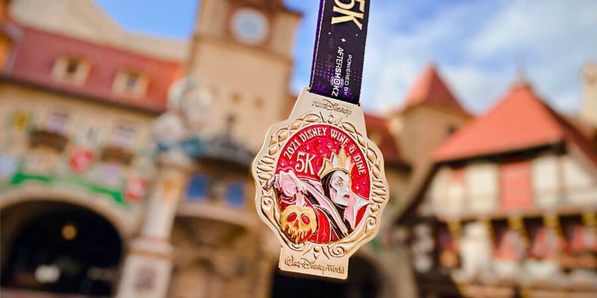 A Disney World guest holds up a medallion for the upcoming Disney Wine & Dine Half Marathon Weekend in November