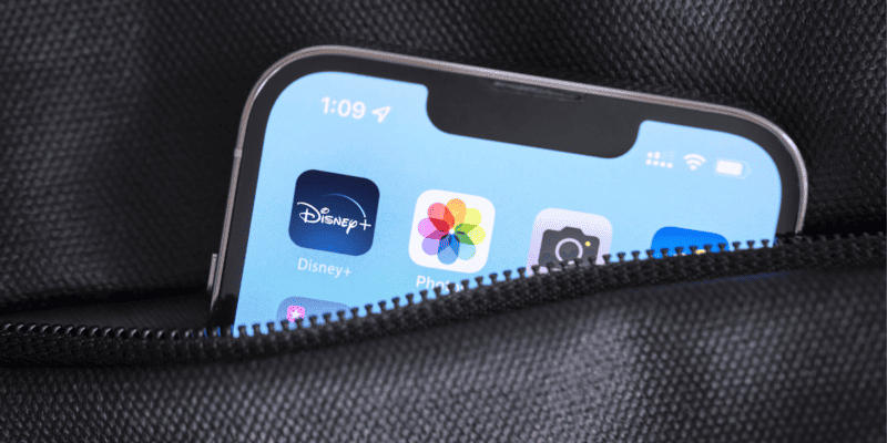 The Disney+ App photographed on a phone screen within the zipper compartment of a bag