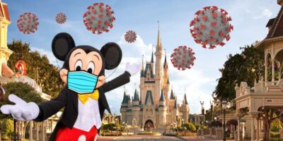 Mickey Mouse in front of Magic Kingdom wearing a face mask with COVID viruses floating in the background with this Disney World travel issue.