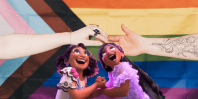 Hands Joined against Progress Pride Flag by Lisett Kruusimäe (Pexels) with Mirabel and Isabela from Disney Animation's movie Encanto in the foreground