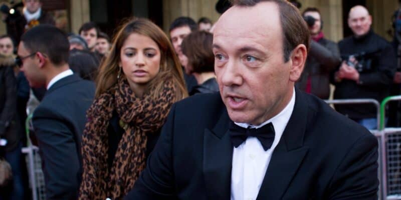 Kevin Spacey in a tuxedo signing an autograph