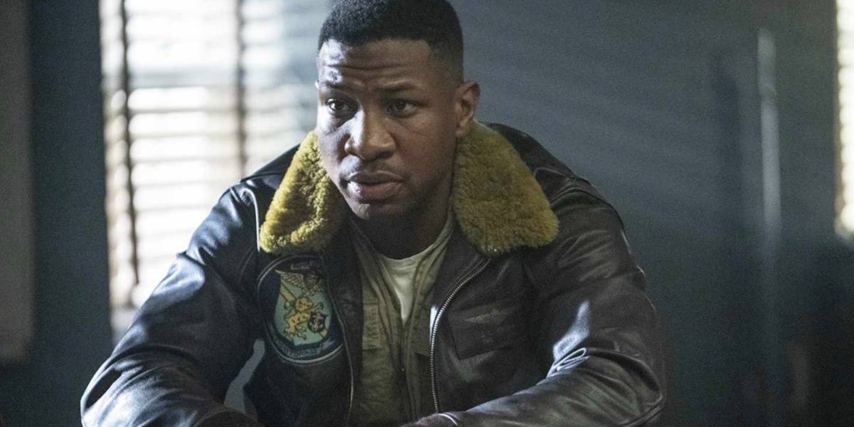 Jonathan Majors wearing a flight jacket in an office