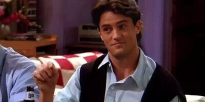Chandler Bing (Matthew Perry) wearing a button up shirt with a vest on friends. Smirking, probably saying something sarcastic.