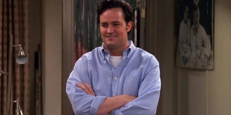 Chandler Bing in a blue shirt, smiling with his arms crossed on Friends