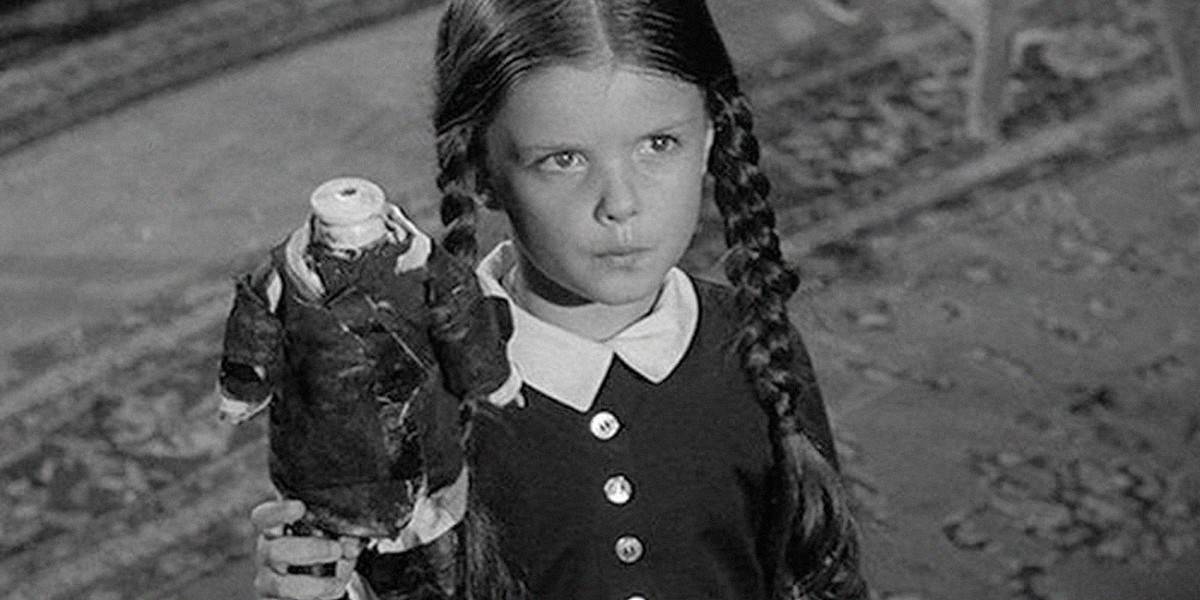Wednesday Addams (Lisa Loring) holding a headless doll