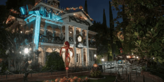 The Haunted Mansion Holiday exterior, shown at night. The historic white mansion is decked out in Christmas decorations and pumpkins, inspired by 'The Nightmare Before Christmas.'
