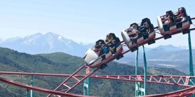 Guest ride a roller coaster with mountains in the background