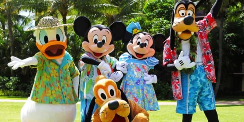 Donald, Mickey, Minnie, Goofy, and Pluto posing in Hawaiian clothes in front of tropical trees as Disney guests face potential evacuation in Hawaii.