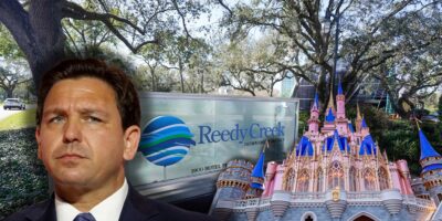 Governor Ron DeSantis frowning with the Reedy Creek signage in the background with the Cinderella Castle to the right.