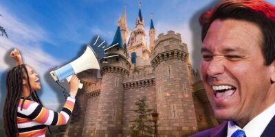 An angry woman yelling into a megaphone with Ron DeSantis smiling and laughing, all taking place in front of the Cinderella Castle at Magic Kingdom at Disney World.