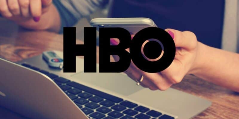 A woman at a computer with a smartphone, with the HBO logo superimposed over her