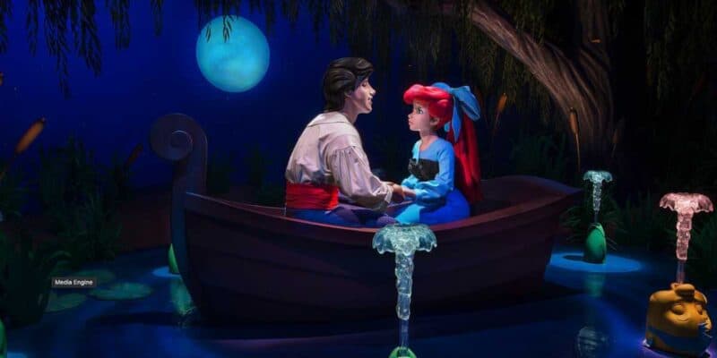 A red-haired girl in a blue dress and a dark-haired man in a white shirt with a red sash sit at the bow of a boat holding hands, illuminated by the moonlight. They are surrounded by glowing water fountains and dark, mysterious trees, reminiscent of enchanting Disneyland attractions.