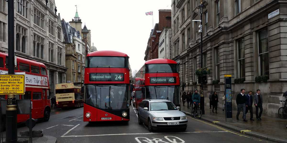 Two red London buses and car on street