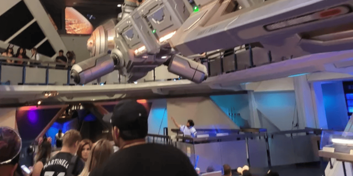 Guests exit the Space Mountain queue, which is brightly lit.