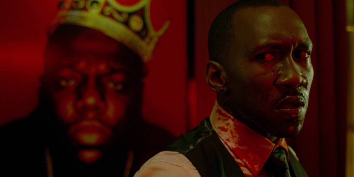 Mahershala Ali covered in blood in front of a painting of Biggie Smalls