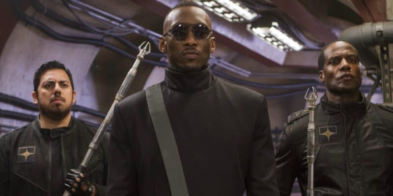 Mahershala Ali walking down a hallway with two guards