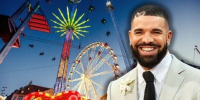Drake smiling in a suit in front of a theme park.